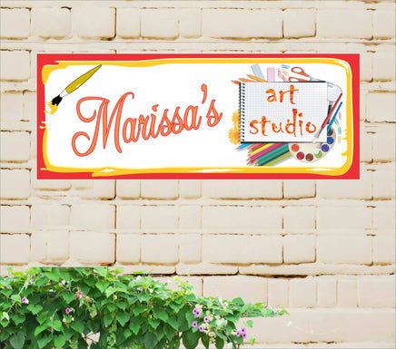 Personalized art studio sign decorated with illustrations of colored pencils, scissors, a sketch pad, paint brushes, and various art supplies.