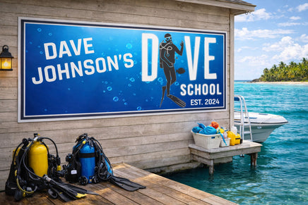 Custom dive school sign mounted on seaside dock wall with scuba gear nearby