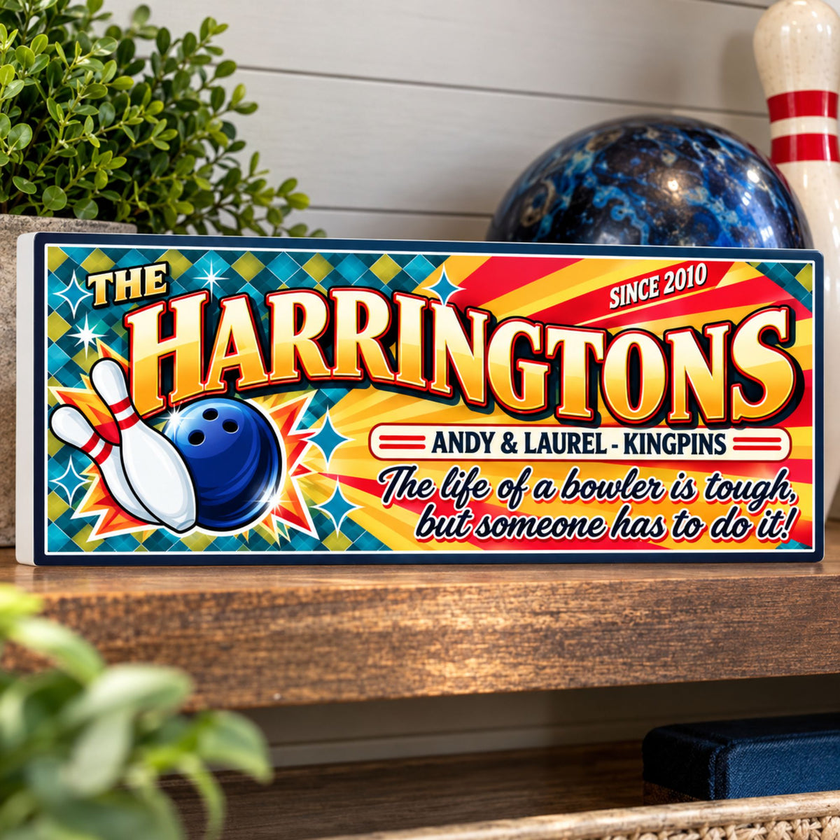Custom bowling sign displayed on a rustic shelf with a blue bowling ball and bowling pin in a game room.