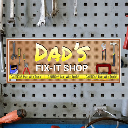 Personalized 'Dad’s Fix It Shop' sign with an editable text feature, showcasing tools on a pegboard background and yellow caution tape accents.