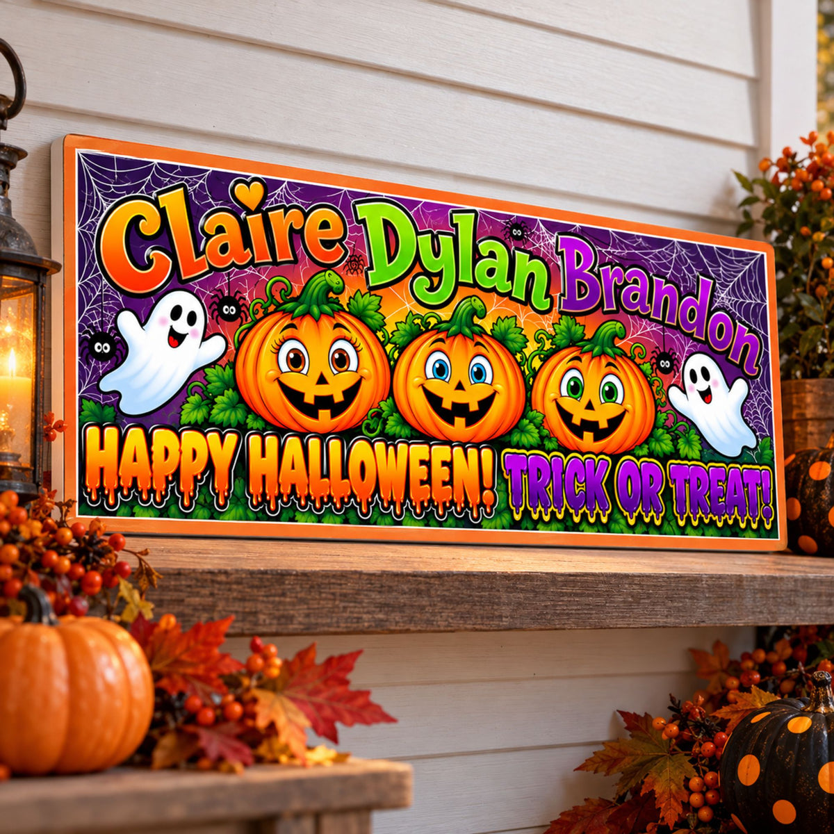 Personalized Halloween sign with three smiling pumpkins, friendly ghosts, spiderwebs and colorful lettering displayed on a decorated fall porch.