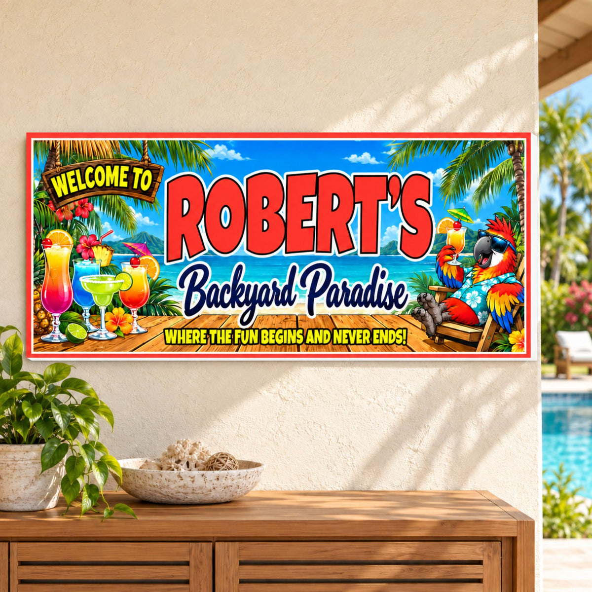 Personalized tropical sign mounted on a light backyard wall near a pool, showing its red border and white PVC edge.