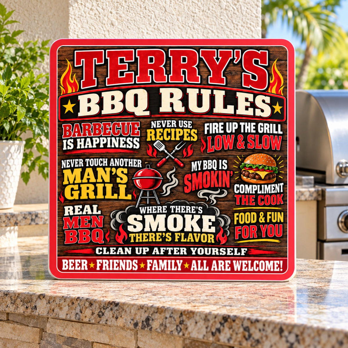 Personalized BBQ Rules sign displayed on a stone outdoor kitchen counter with tropical greenery in the background.
