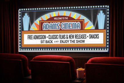 Home theater room with a vintage cinema marquee style wall sign, glowing lights, red theater seats and popcorn, designed as personalized movie room decor.