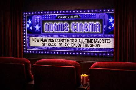 Home theater room with a personalized cinema marquee wall sign, glowing movie-style lights, red theater seating, curtains, and popcorn on the armrest.