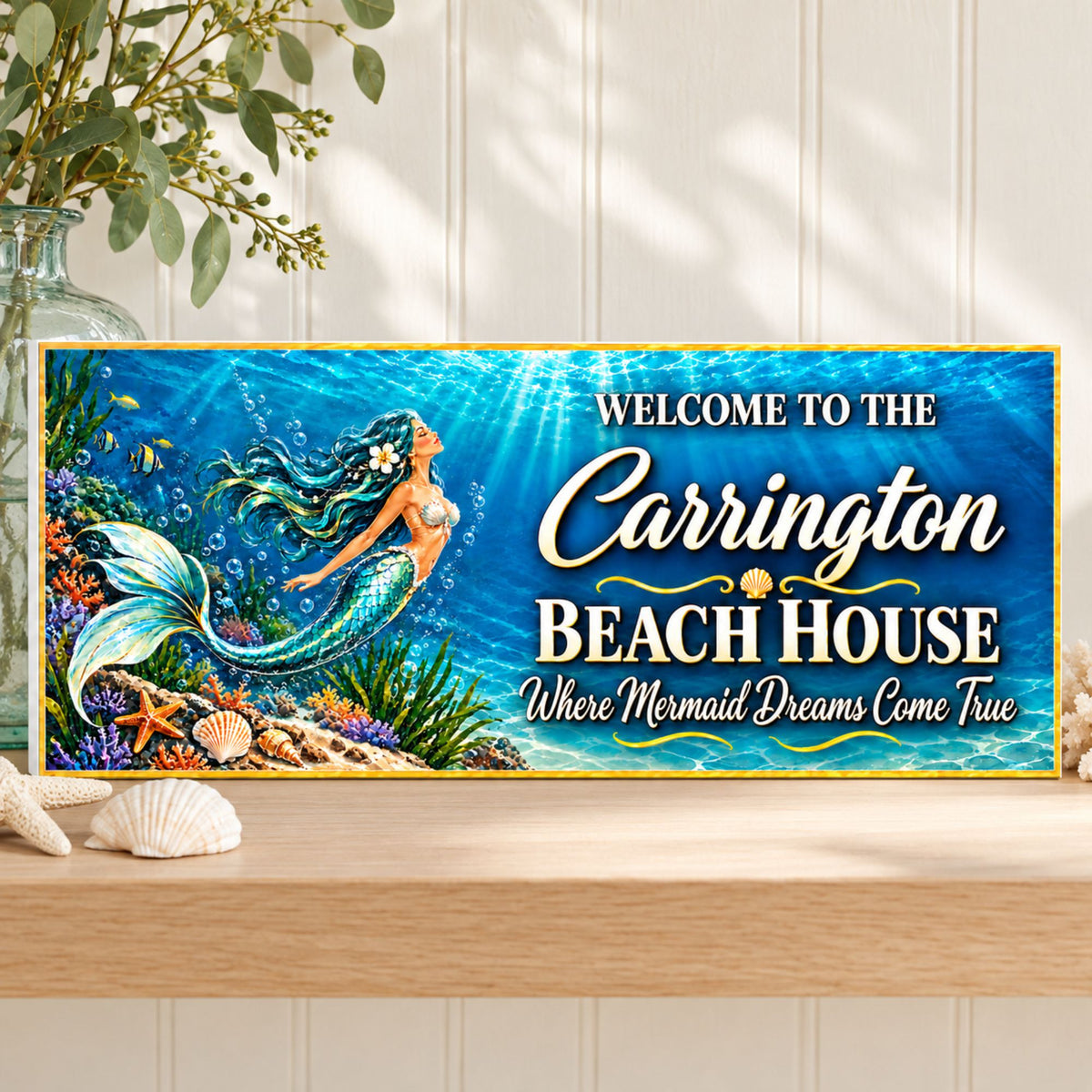 Personalized mermaid beach house sign resting on a light wood shelf against white paneling, with greenery and a visible white PVC edge.