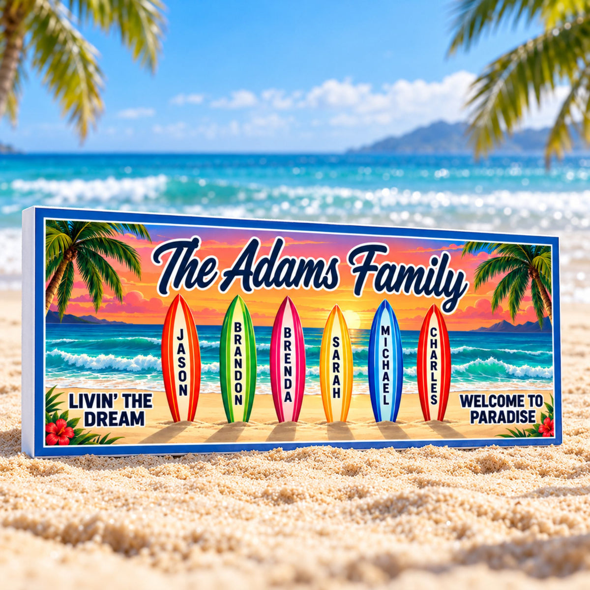 Personalized surfboard family sign standing on a sandy beach at a slight angle, with the white PVC edge visible on the left and turquoise ocean behind it.