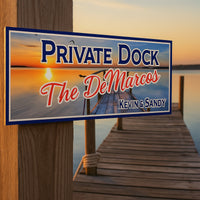 Custom dock sign displayed on a wooden pier overlooking a calm lake at sunset