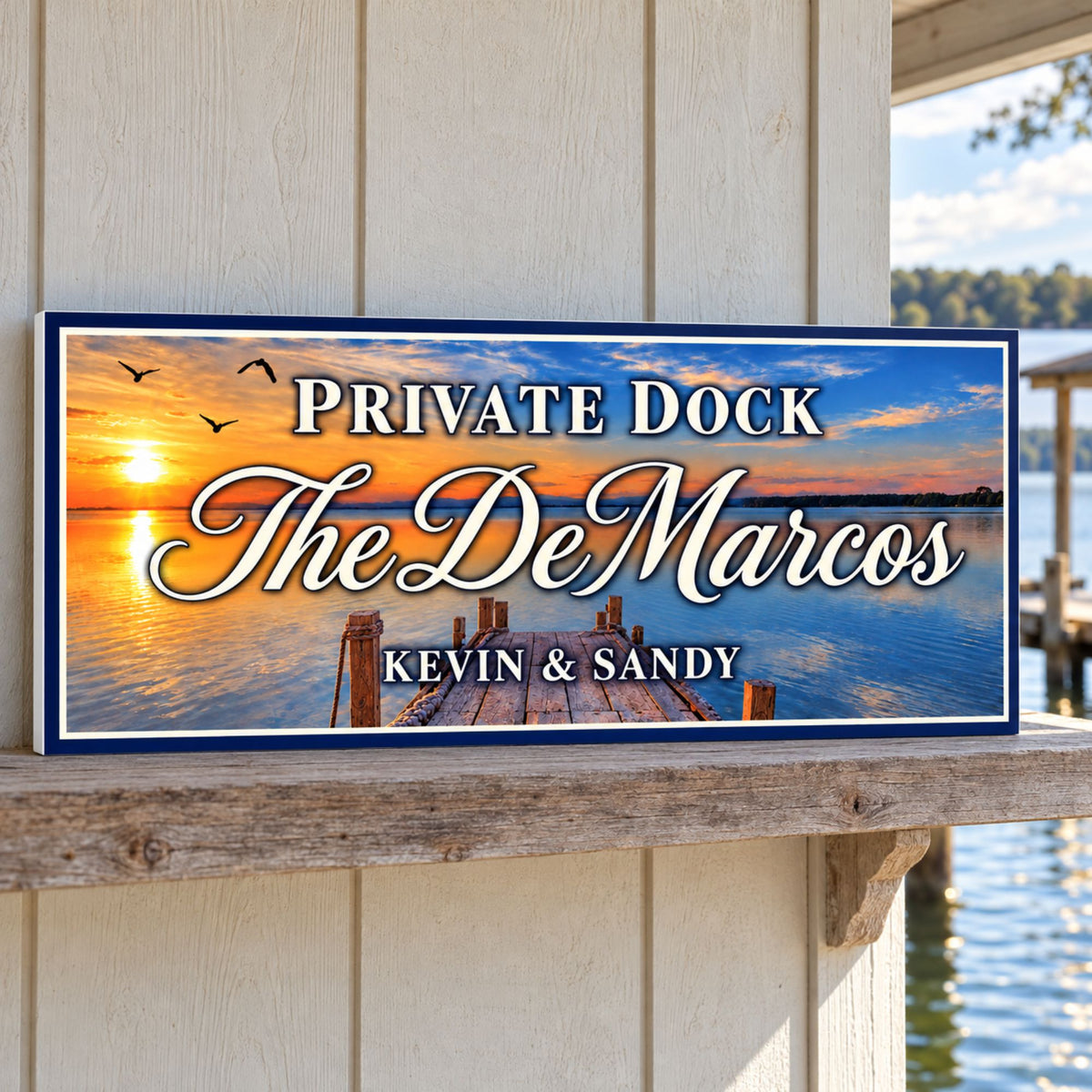 Personalized Private Dock sign with a sunset lake scene and cream lettering, displayed on a weathered boathouse shelf beside the water.