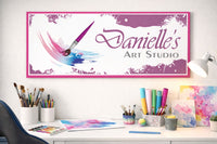 custom art studio wall sign displayed above an art desk with brushes, paints, and watercolor supplies
