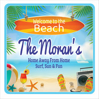 personalized beach house sign with surfboard flip flops drink and seashells on a coastal scene