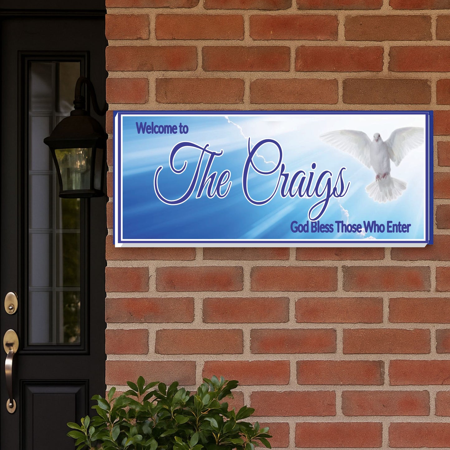 Religious family name sign displayed on a brick home exterior wall
