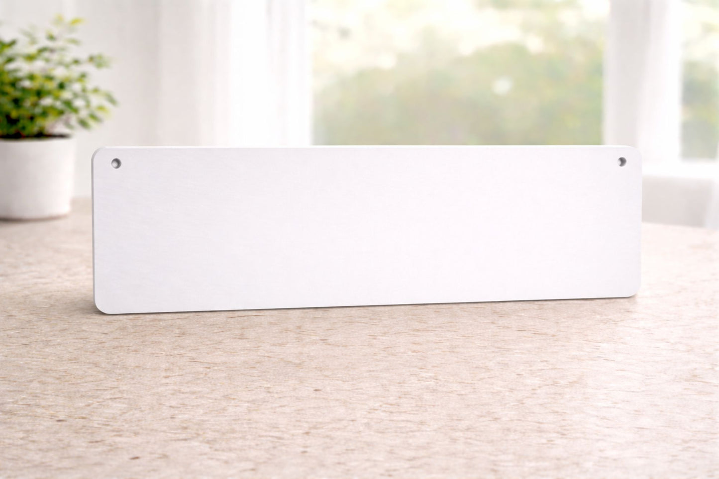 back view of rectangular aluminum sign with rounded corners and mounting holes in the top corners, resting on a tabletop indoors