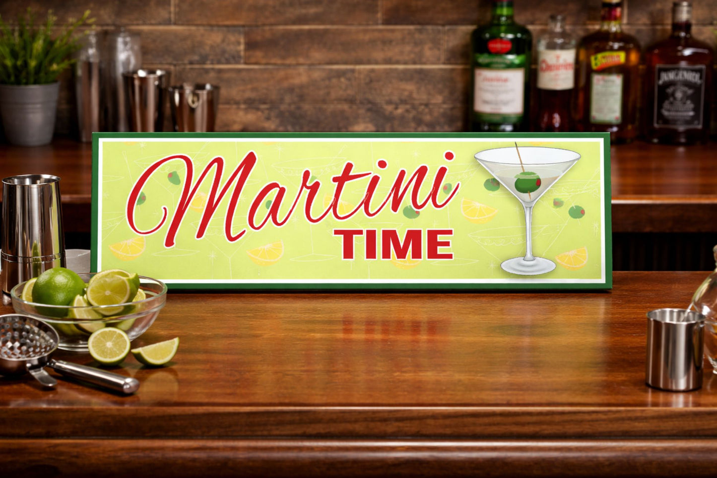 lifestyle image of martini time sign sitting on wooden bar top with cocktail tools and limes