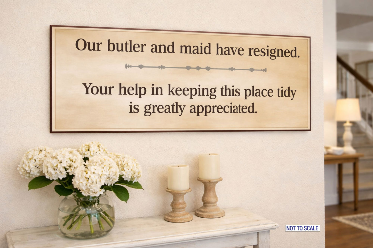 guest room humor sign displayed above console table with flowers and candles