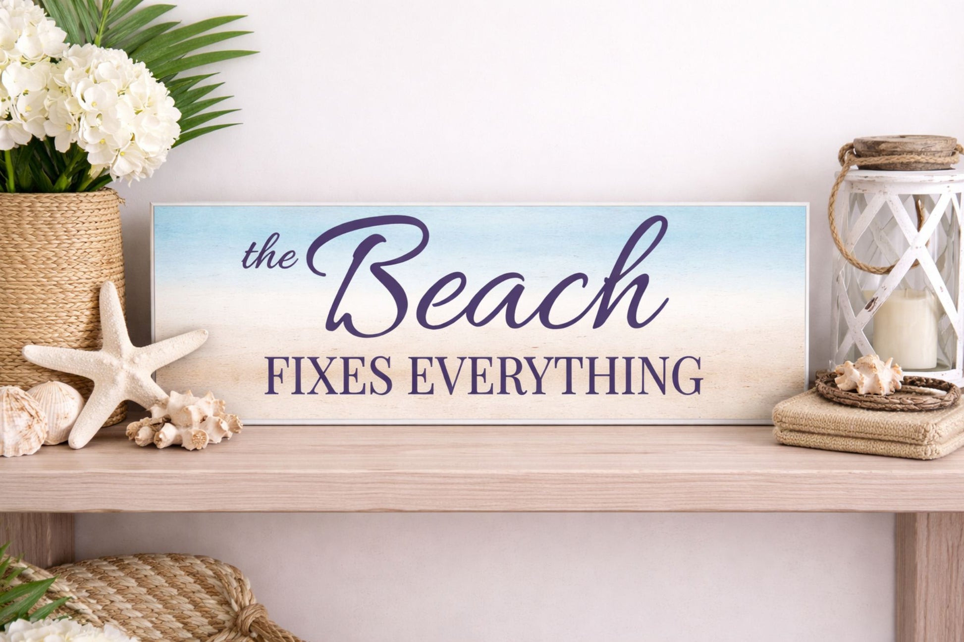 the beach fixes everything sign displayed on shelf with coastal decor and neutral styling