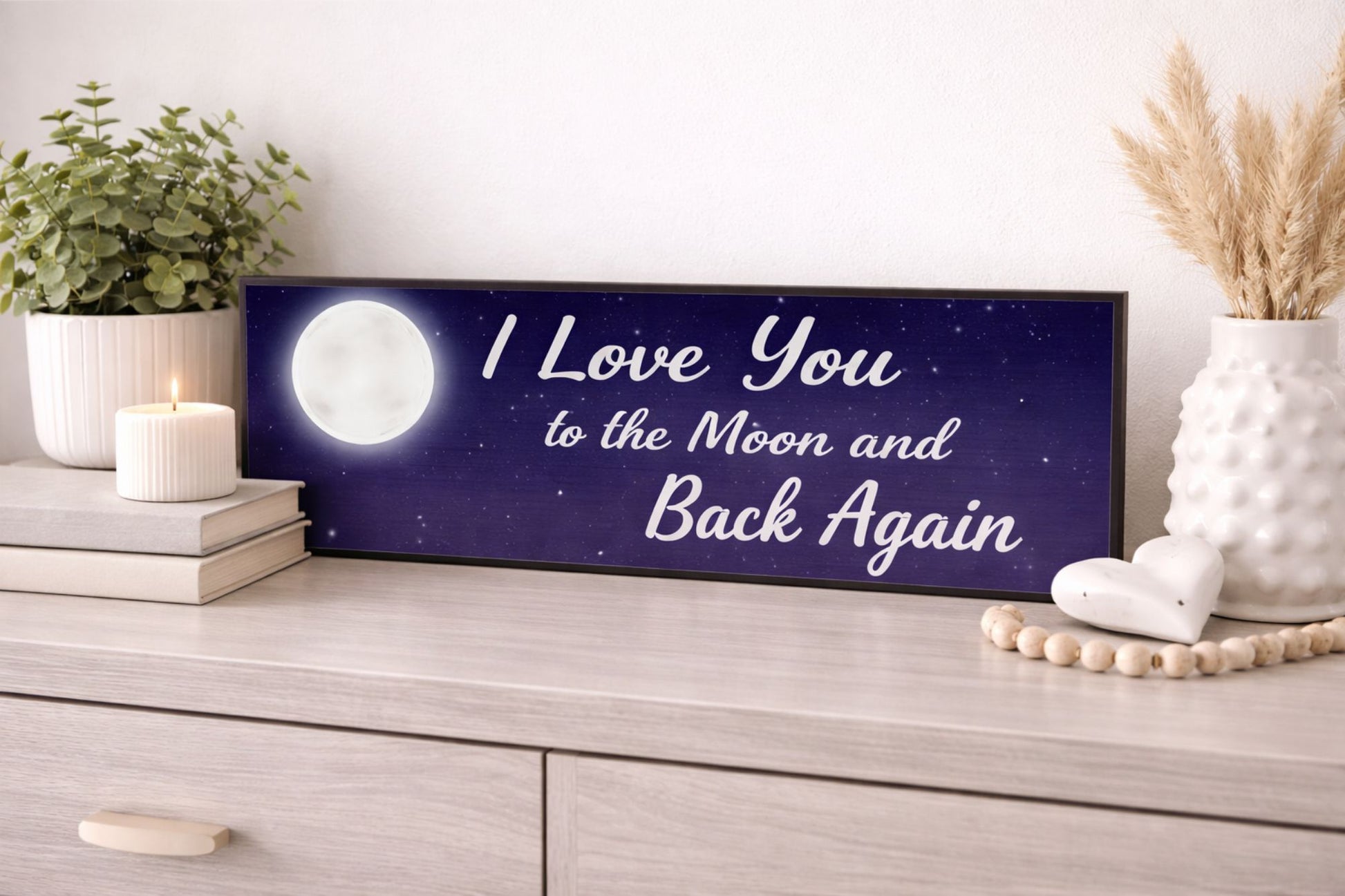 moon and stars quote sign resting on dresser with plant candle and neutral home decor