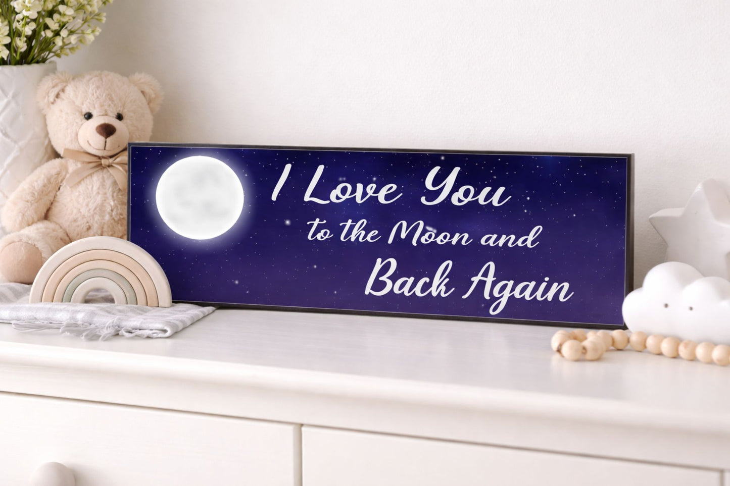 i love you to the moon and back again sign displayed in nursery with teddy bear decor