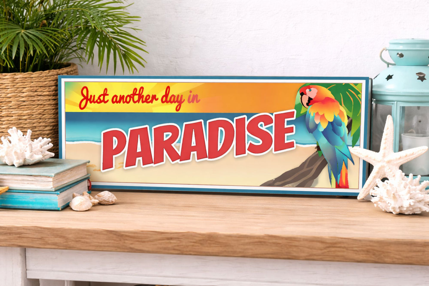 lifestyle image of narrow beach sign displayed on shelf with coastal decor and plants