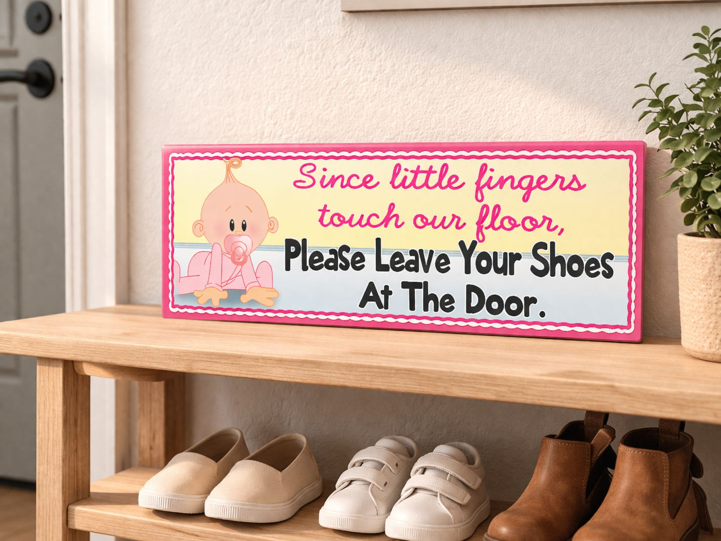 close up of pink baby shoes off sign sitting on entryway table near front door with keys and plant soft natural lighting home interior
