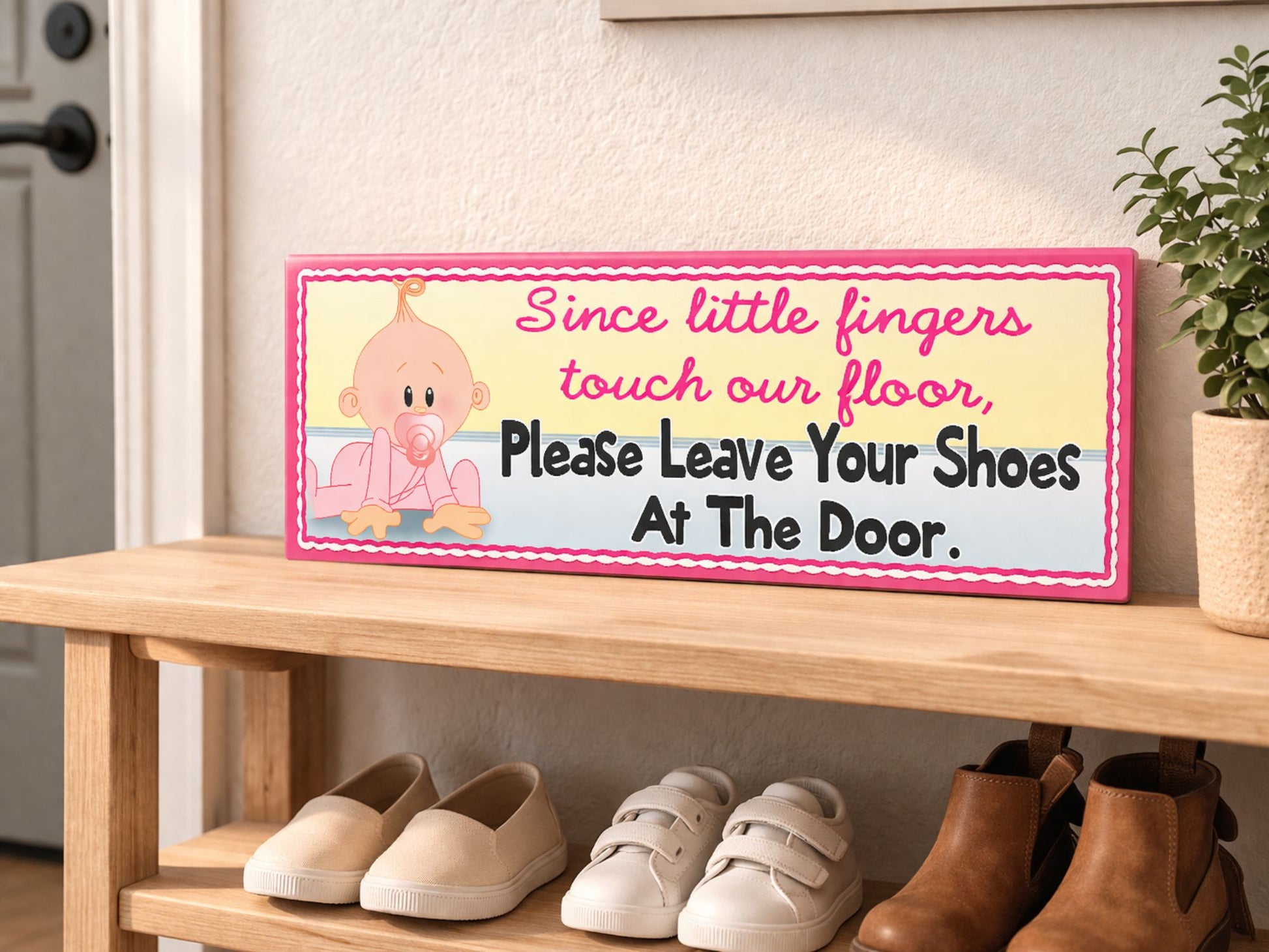 close up of pink baby shoes off sign sitting on entryway table near front door with keys and plant soft natural lighting home interior