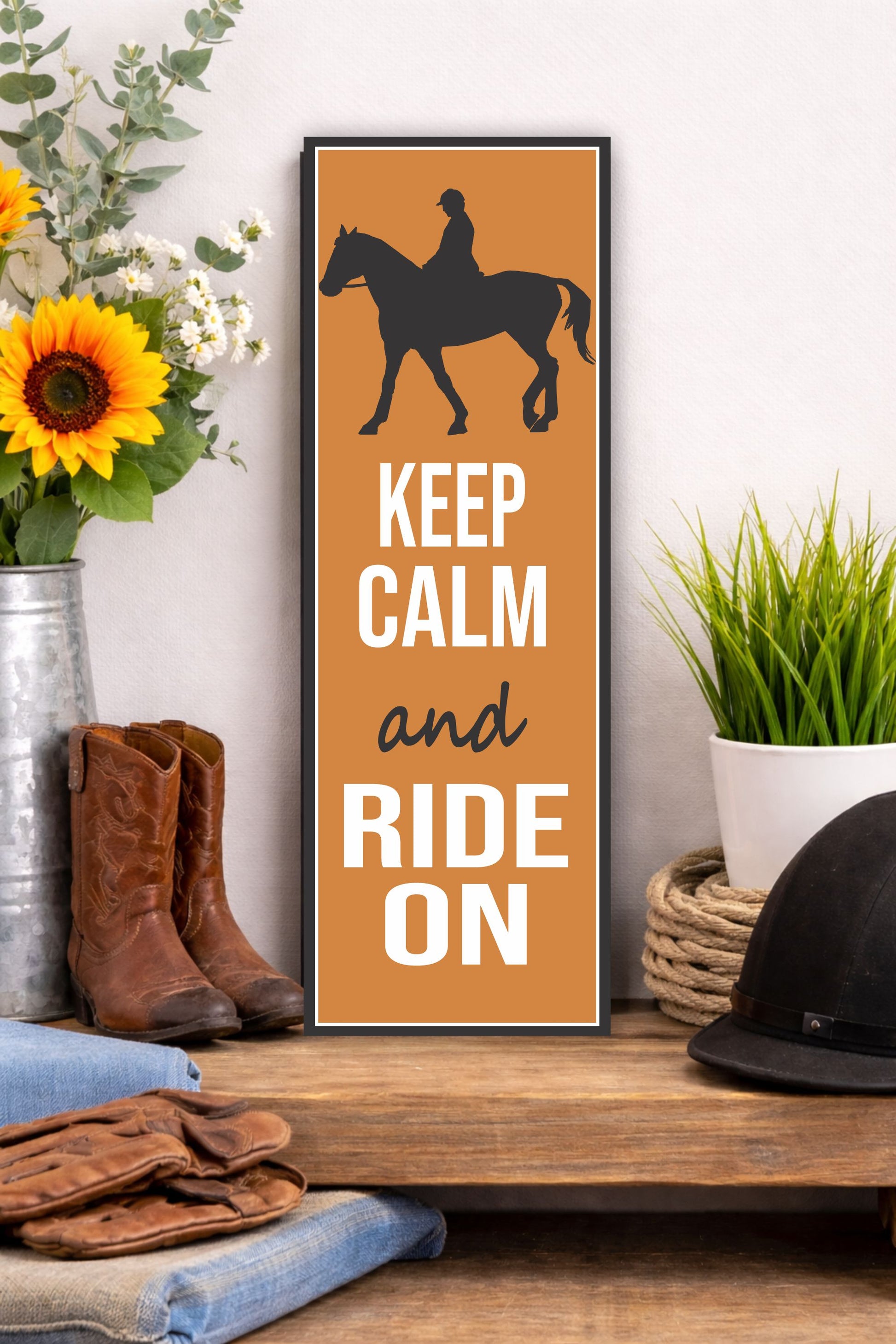 Keep calm and ride on horse sign displayed on wooden shelf with western decor boots helmet and sunflowers