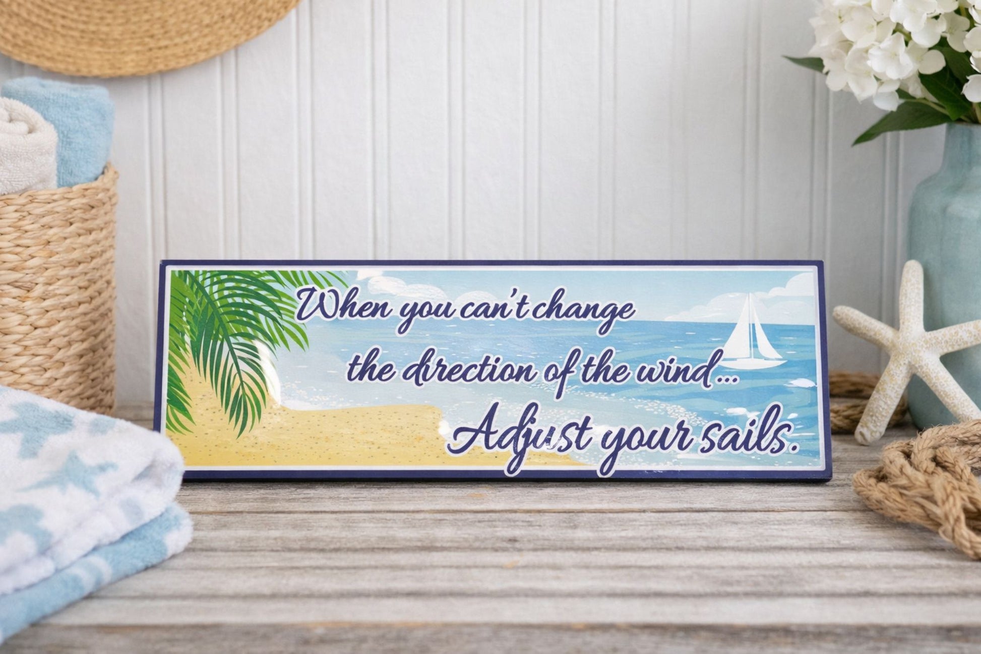 coastal quote sign displayed on entry table with beach decor towels starfish and vase