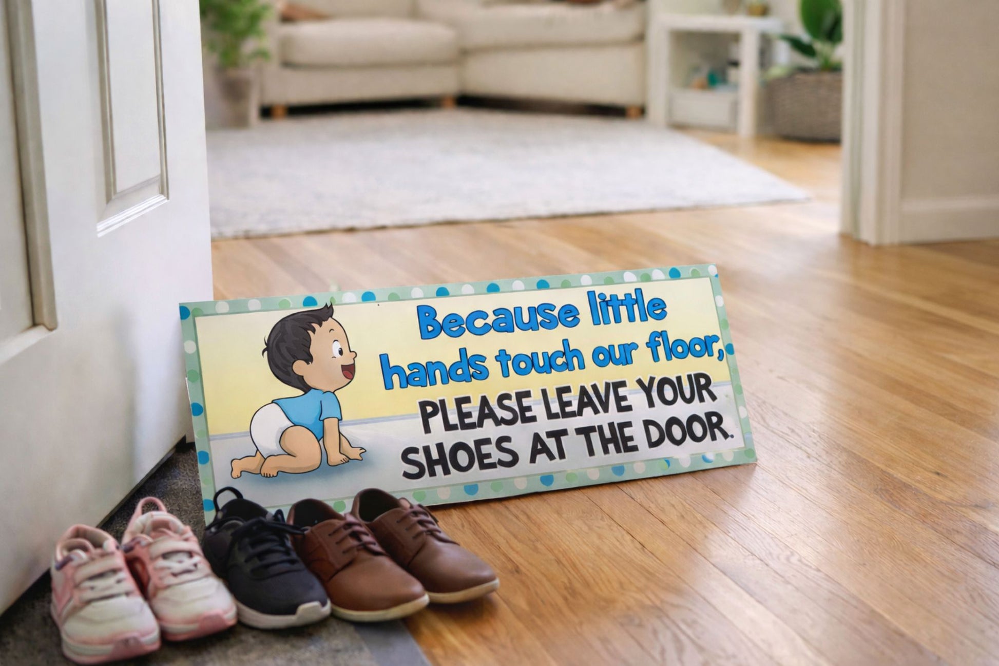entryway scene with baby shoes off sign on floor with shoes beside it in a bright family home