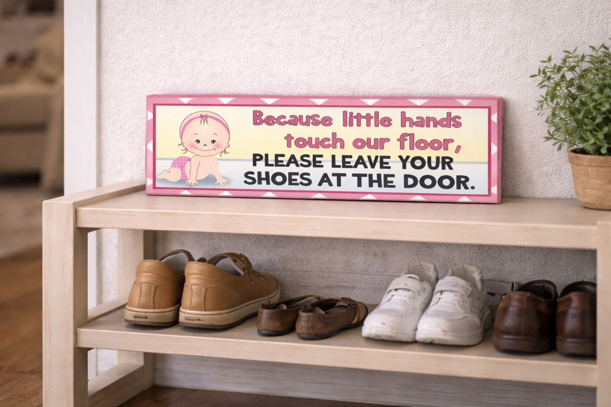 close up of pink baby shoes off sign sitting on wooden shoe rack with neatly arranged shoes in entryway soft neutral home setting