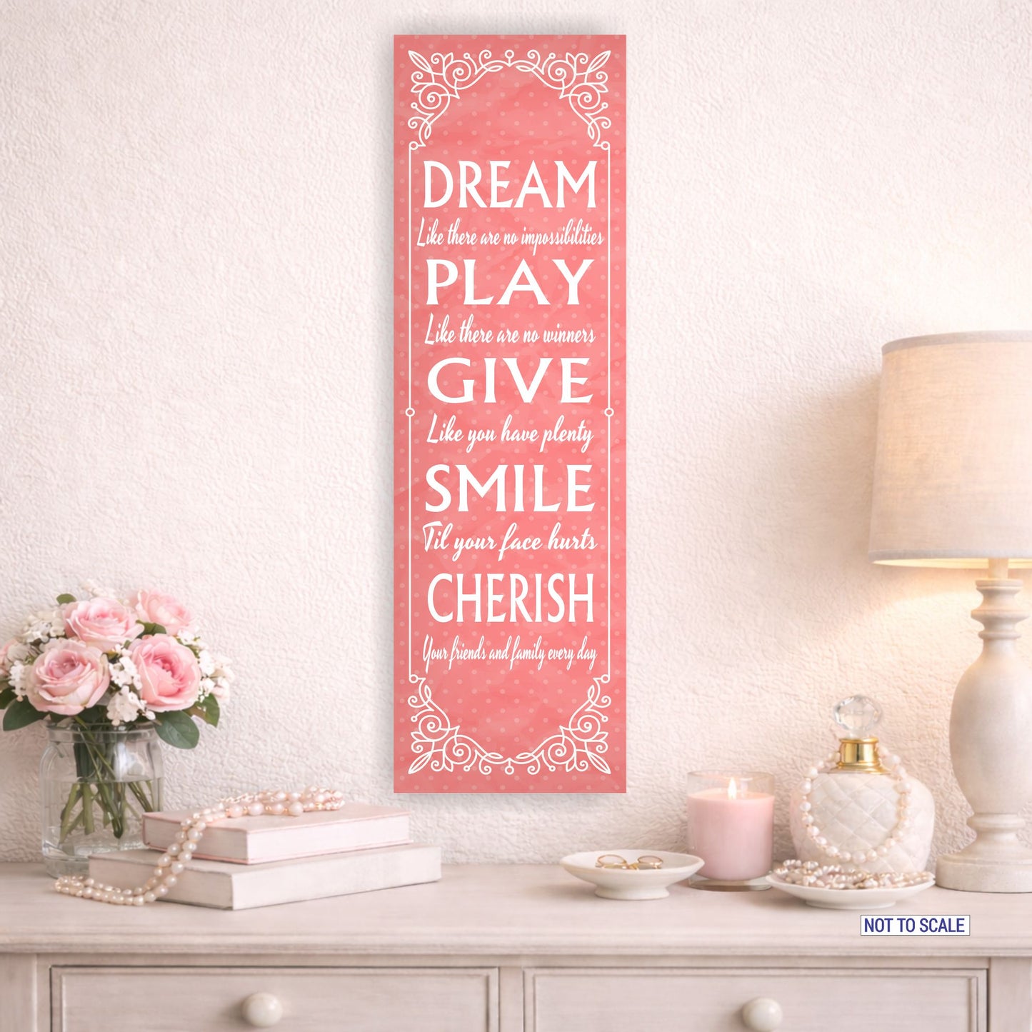 Inspirational pink wall sign mounted above dresser with flowers and lamp