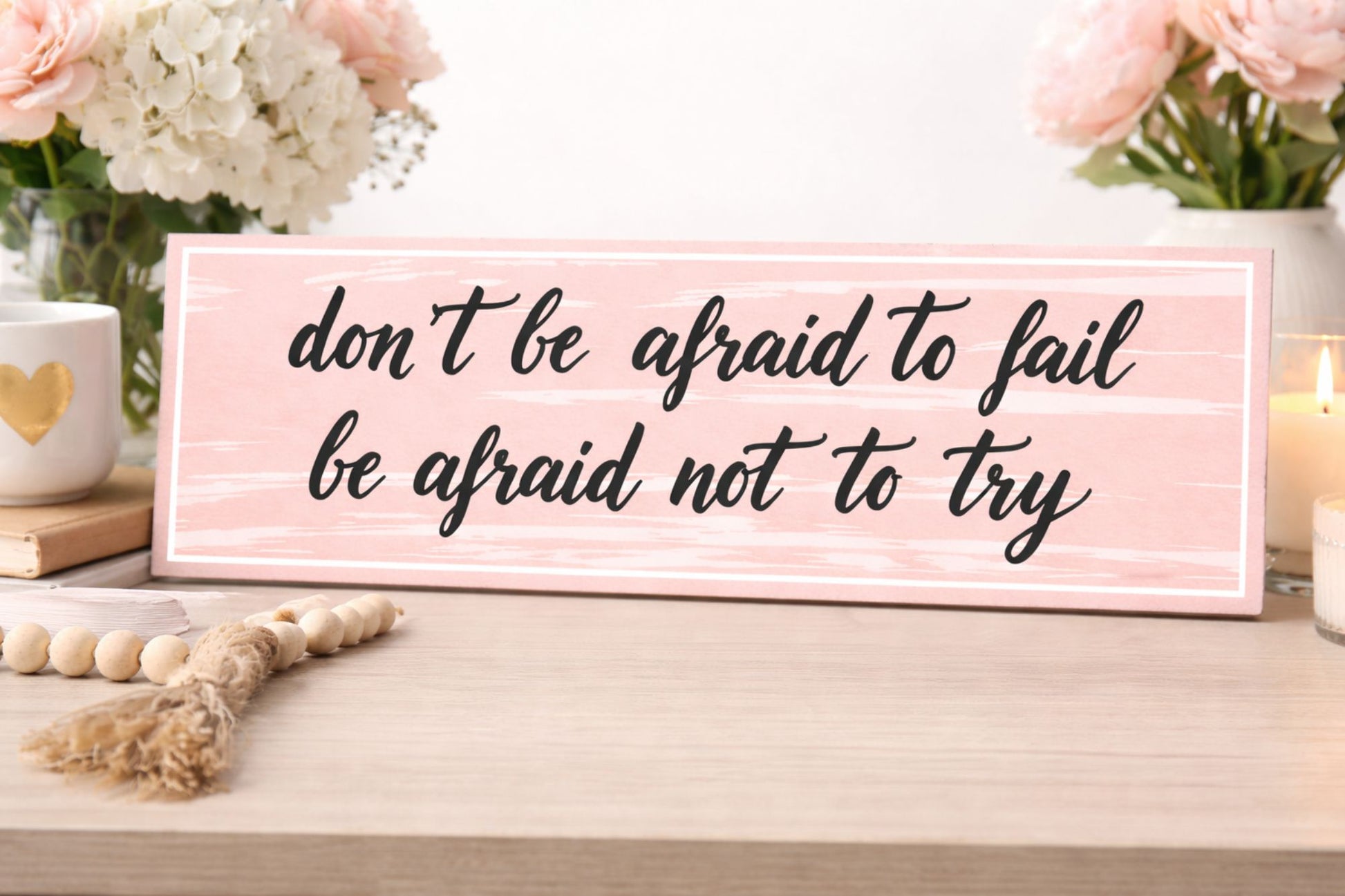 motivational quote sign displayed on shelf with flowers candles and soft decor accents