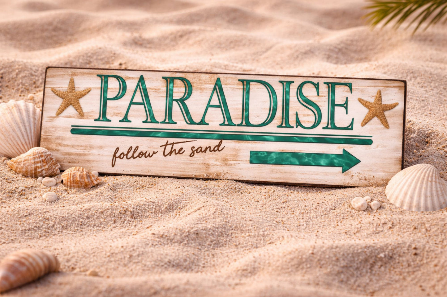 paradise sign displayed in beach sand with shells and starfish