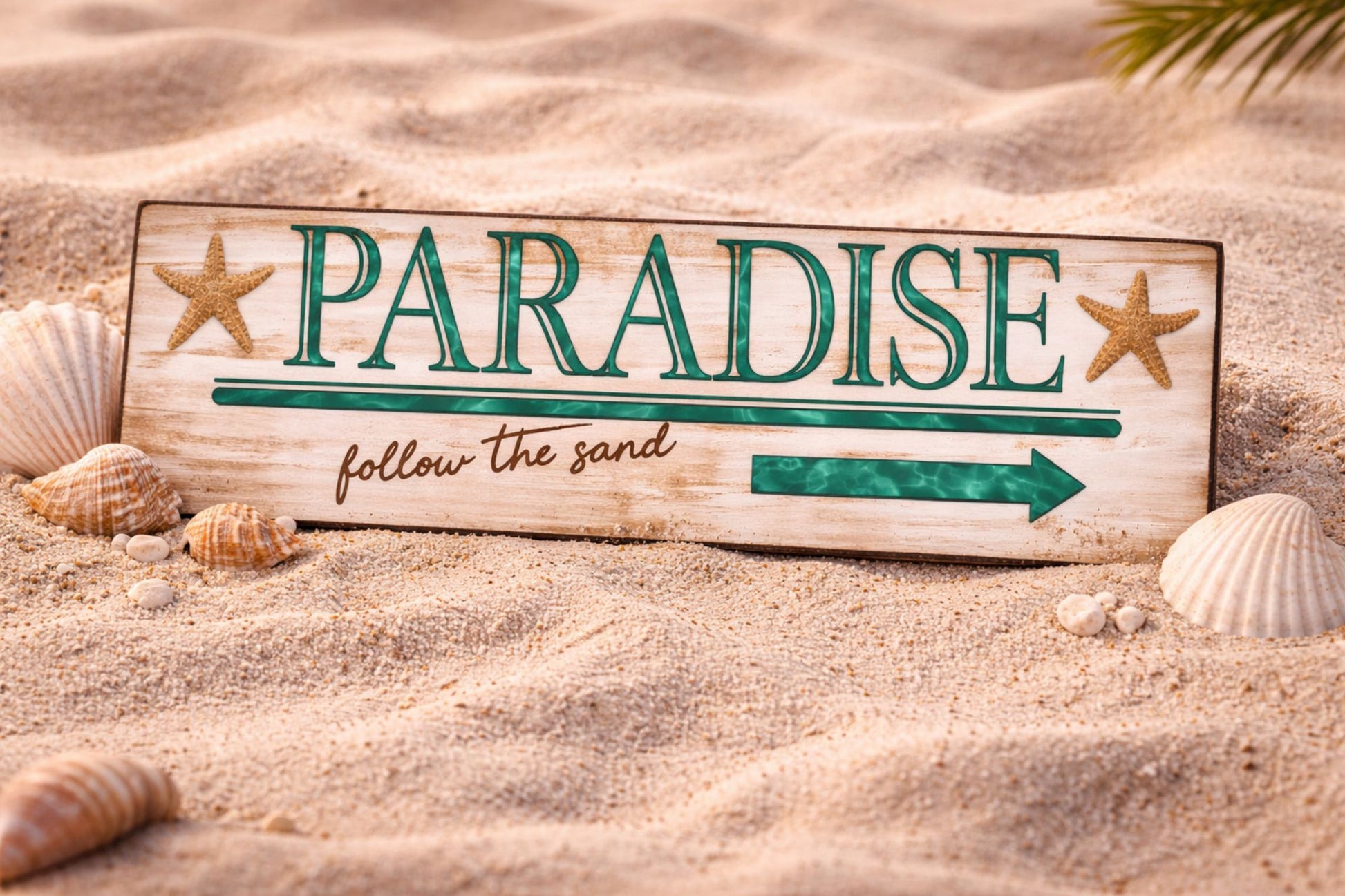 paradise sign displayed in beach sand with shells and starfish