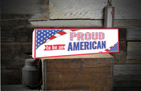  "Proud to Be An American" novelty sign with the USA flag displayed in two corners, symbolizing national pride and patriotism.
