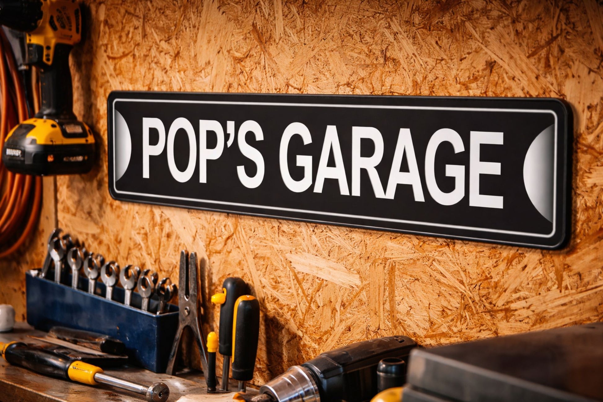 Personalized aluminum garage sign mounted on workshop wall above tools and workbench close-up lifestyle image