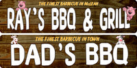 Two personalized barbecue signs displayed on rustic wood — one with pig graphics reading “Ray’s BBQ & Grill,” and one with cow graphics reading “Dad’s BBQ,” showing the available animal graphic options.