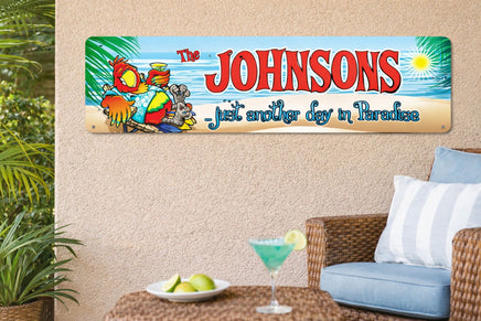 Colorful tropical patio scene featuring a personalized aluminum beach sign mounted on a stucco wall, showing a relaxed parrot in a chair with the phrase “...just another day in Paradise,” surrounded by greenery, wicker furniture, and a cocktail on the table.