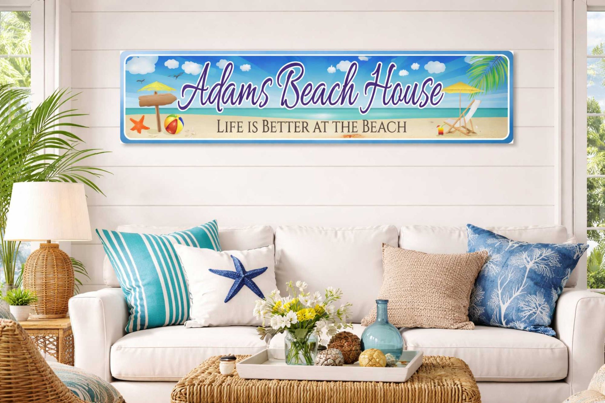 Custom aluminum beach house sign with tropical ocean artwork, personalized name, displayed above a console table in a bright coastal living room.